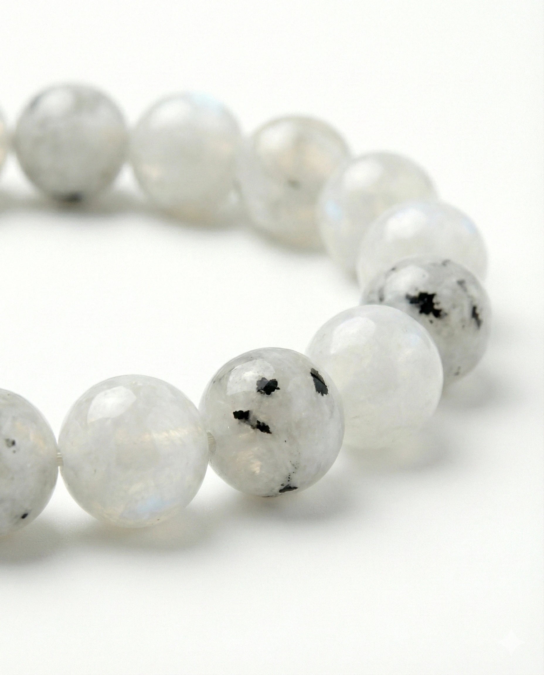 Natural Rainbow Moonstone beaded bracelet featuring 8mm white stones with black tourmaline inclusions on white background.