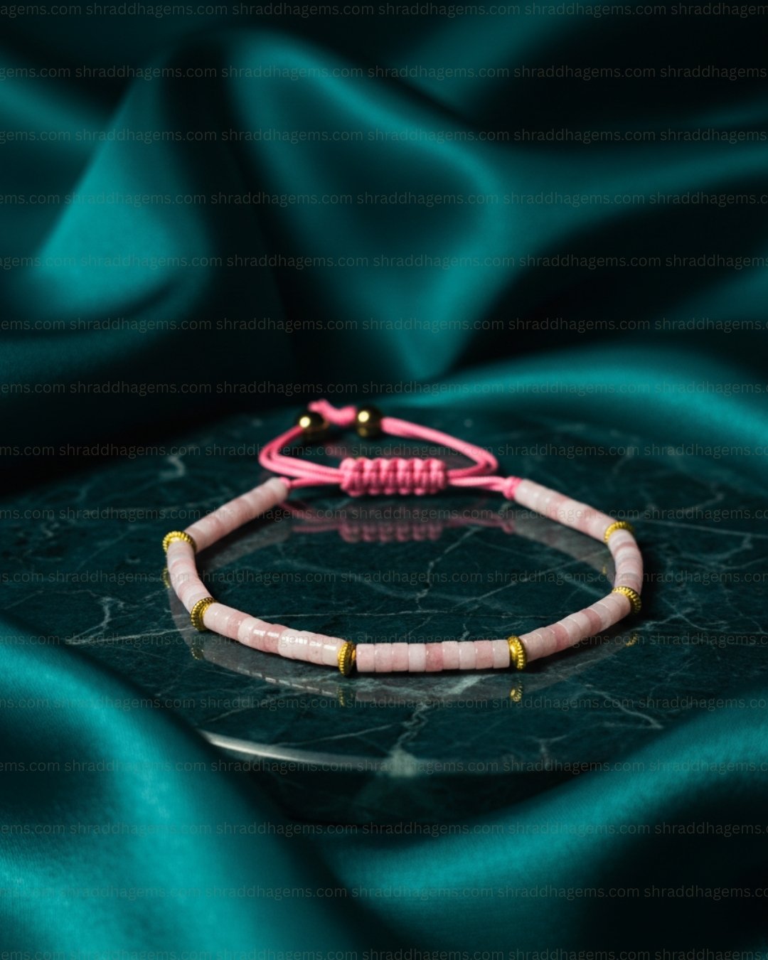 Pink beaded bracelet on a dark green fabric background